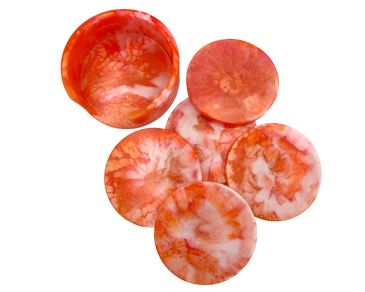 Orange, Pink, and white resin coasters, round, displayed on a white background