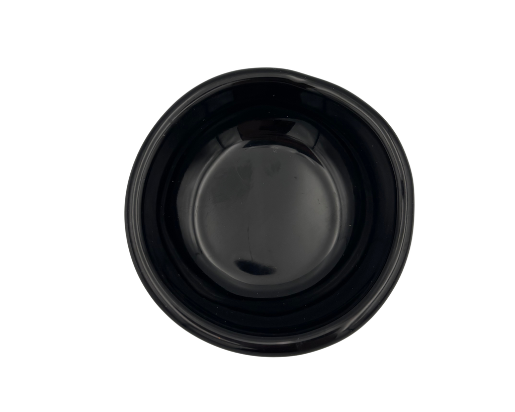A small, glossy black resin bowl with an irregular, organic shape, shown from a top-down perspective on a solid white background.