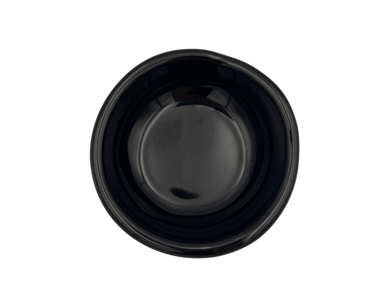 A small, glossy black resin bowl with an irregular, organic shape, shown from a top-down perspective on a solid white background.