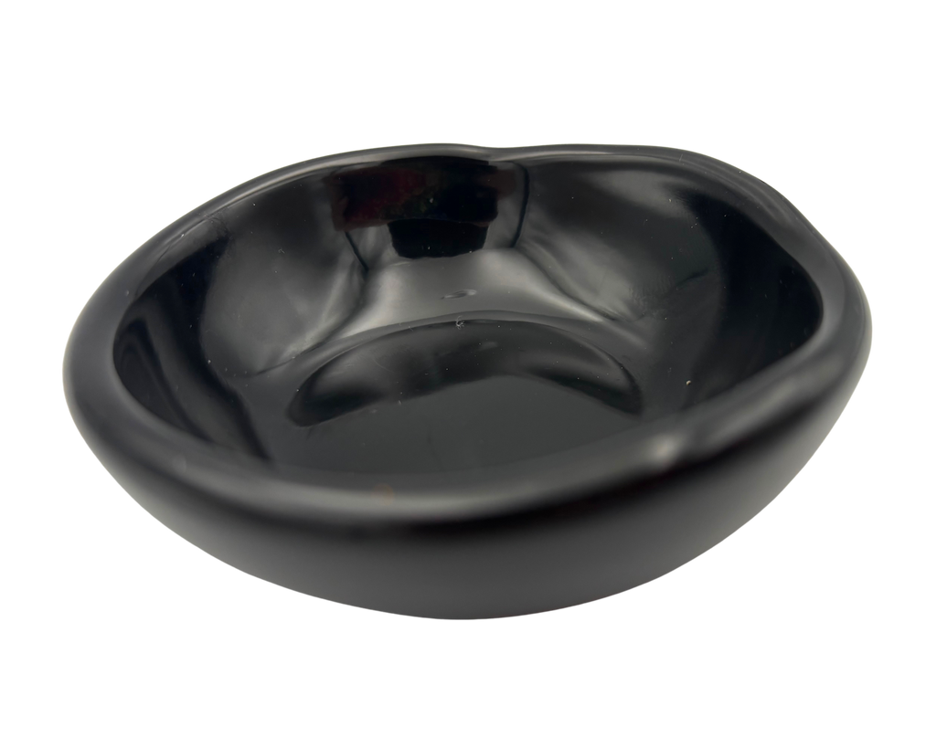 A small, glossy black resin bowl with an irregular, organic shape, shown from a top-down perspective on a solid white background.