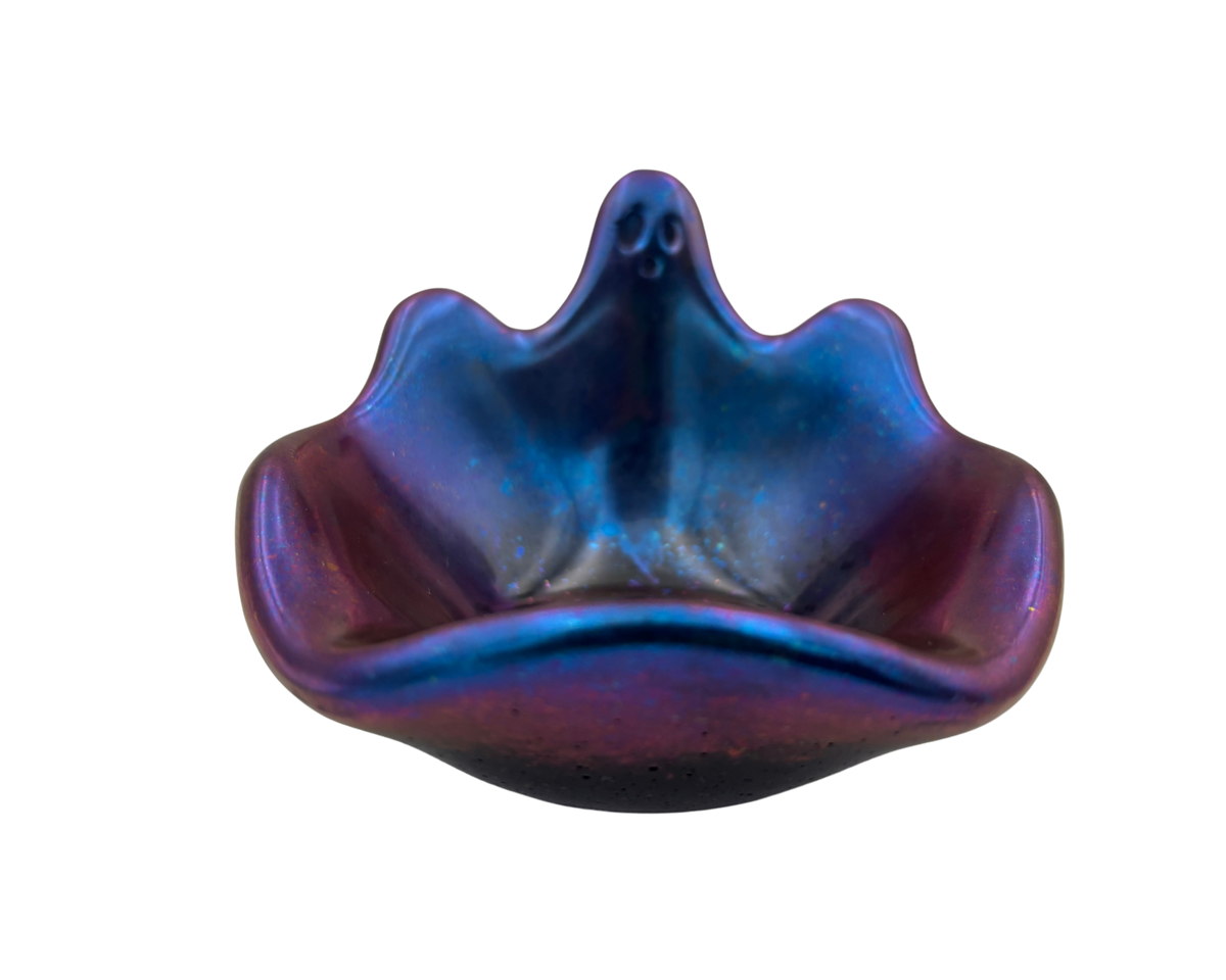 An iridescent resin bowl with a ghost-shaped rim and a small ghost motif on the top, featuring a blue, purple, and pink color-shifting finish on a white background.