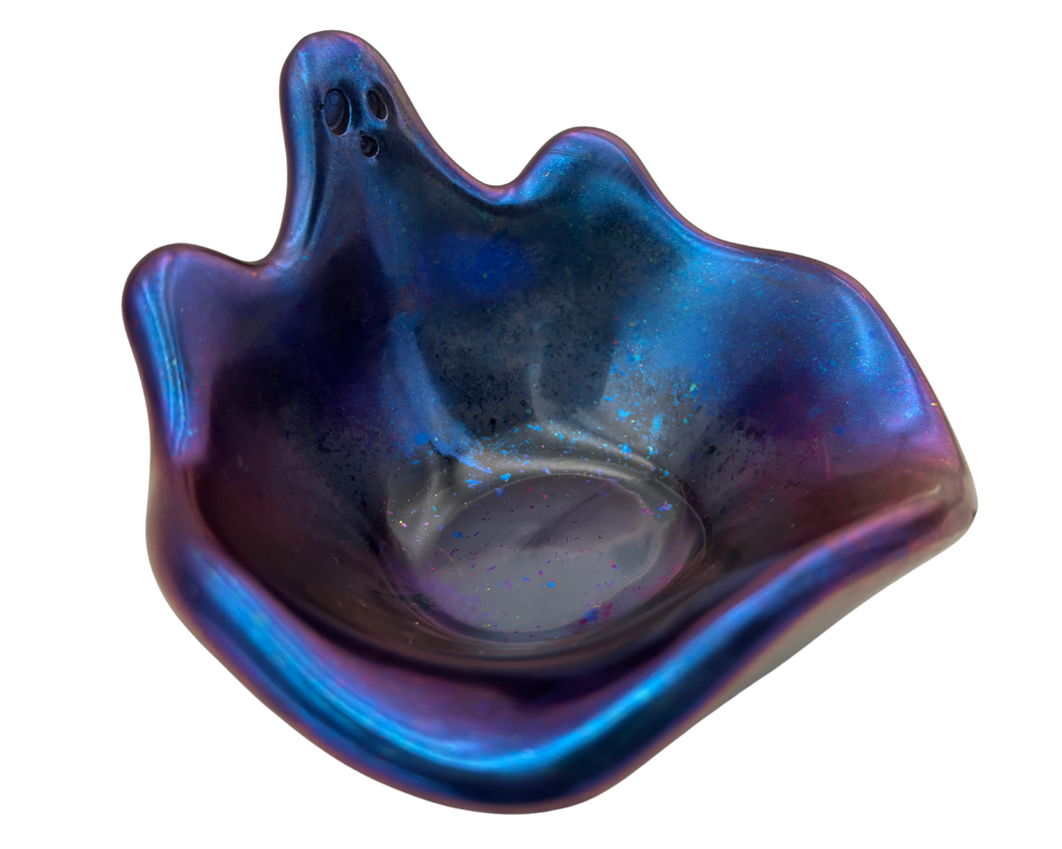 An iridescent resin ghost bowl with a blue and purple color-shifting glaze, featuring a small face detail on the top left, shown on a plain white background.
