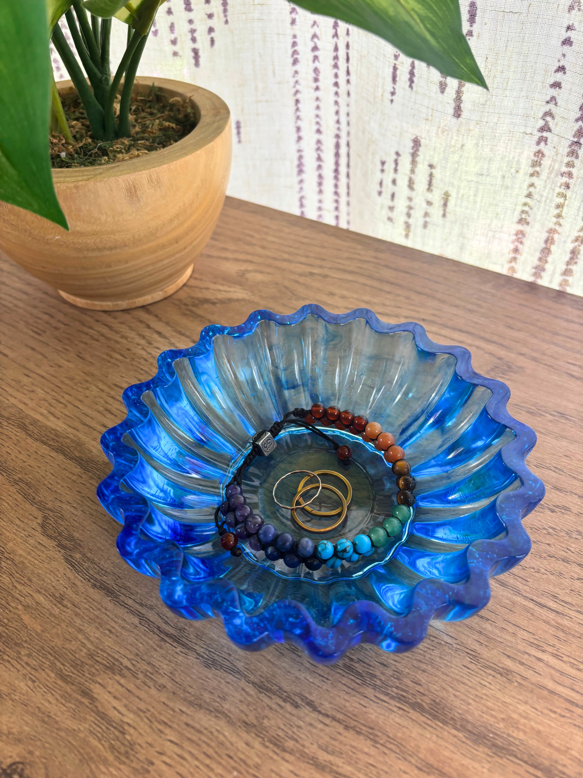 Blue Resin bowl with scalloped edges holding bracelets and rings on a table