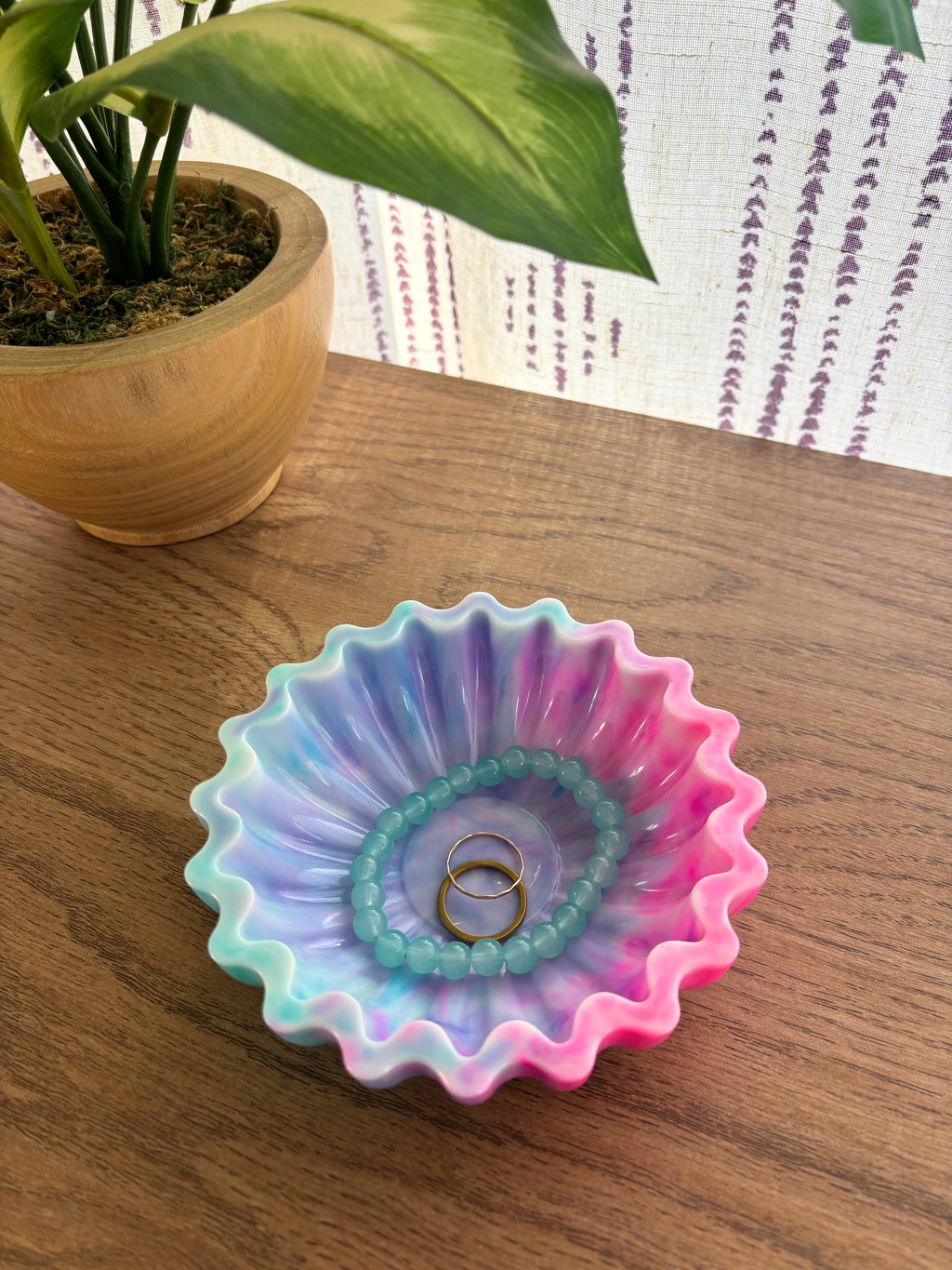 blue and pink resin bowl with scalloped edges with jewelry on table