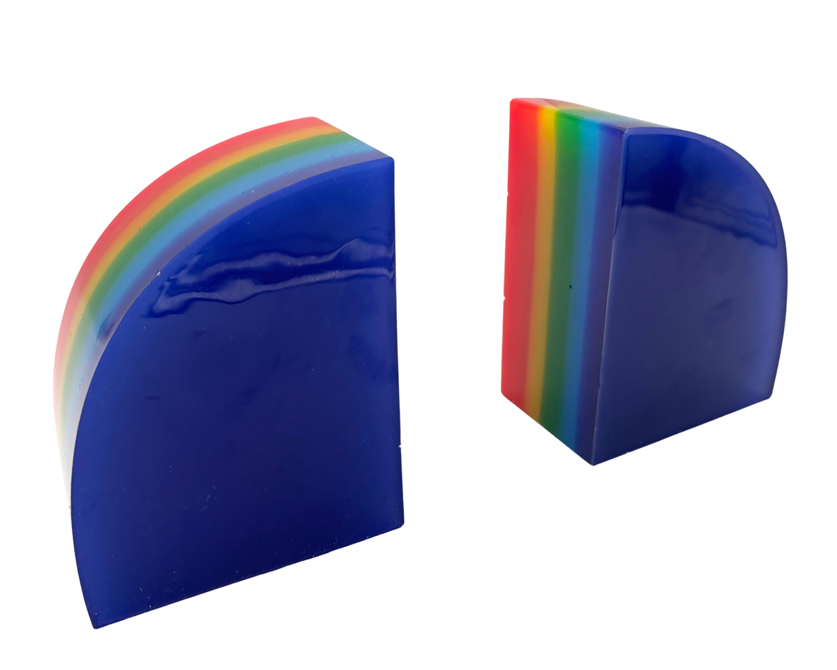 Two glossy blue semicircular bookends with a rainbow-colored striped edge, shown on a plain white background.