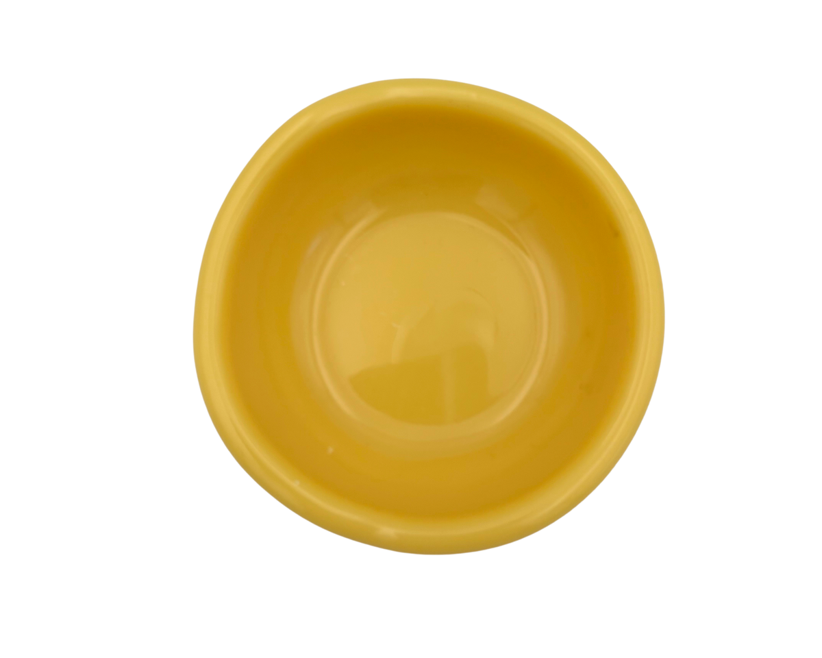 A small, shallow yellow resin bowl with a slightly irregular, organic shape, shown against a plain white background.