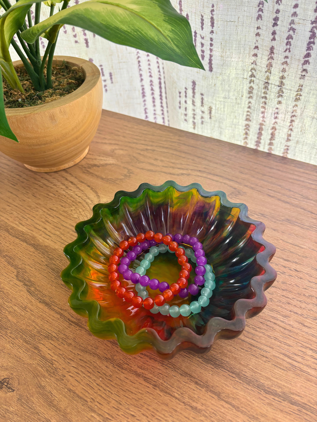 colorful resin bowl with scalloped edges holding bracelets on a table