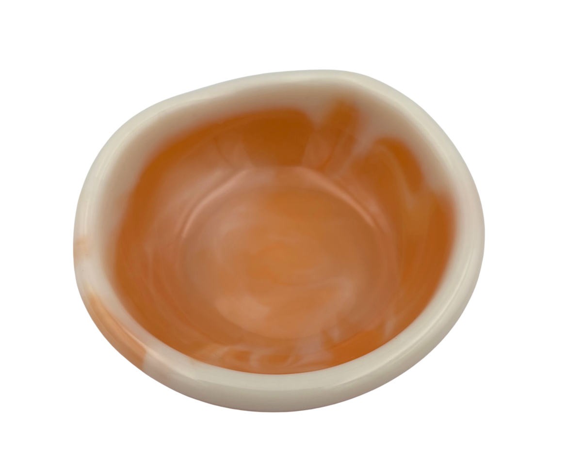 A top-down view of a small, round, off-white resin dish with orange swirls, isolated on a solid white background.