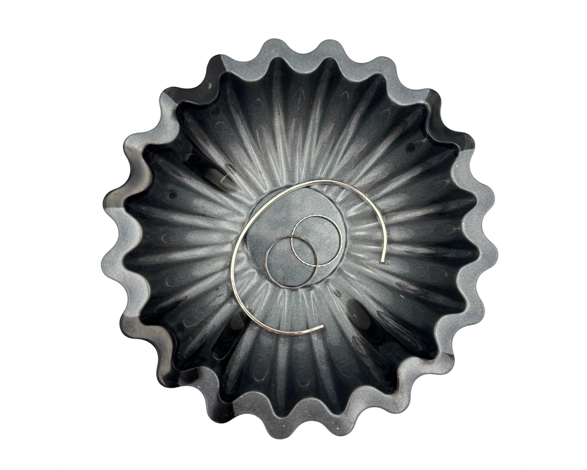 Gray and black resin bowl with scalloped edges holding jewelry