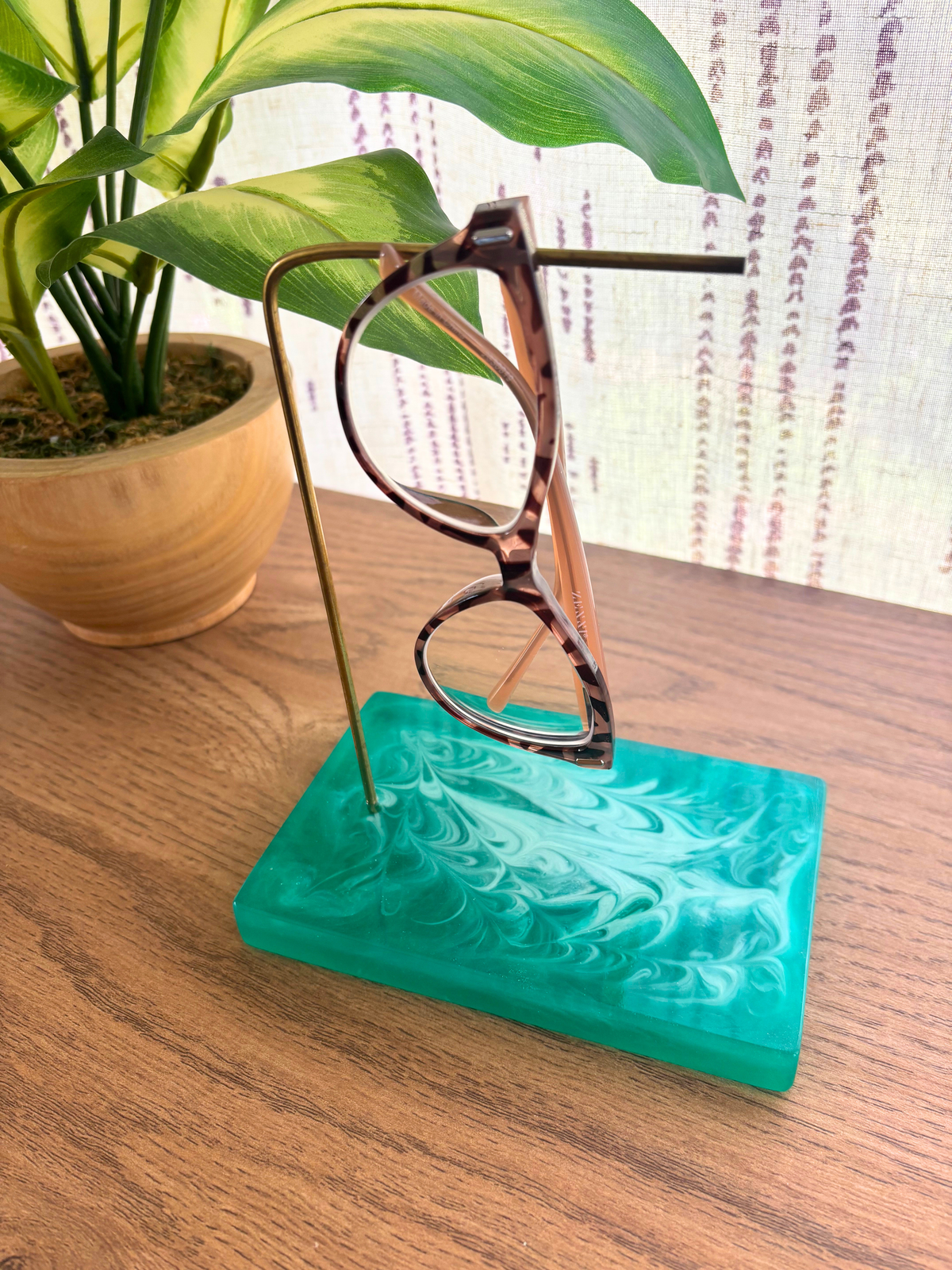 Green resin base glasses holder with pair of glasses on brass rod on table