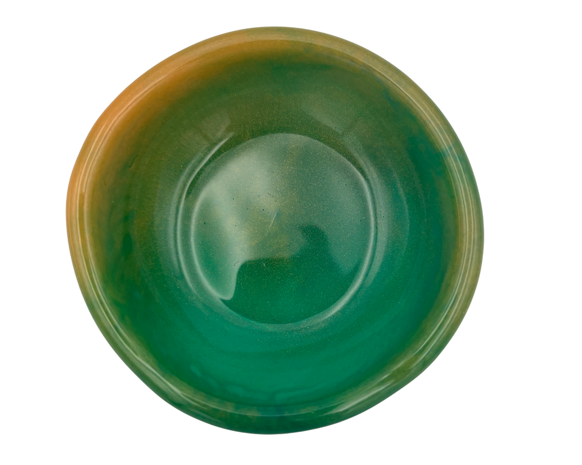 A round resin bowl with a glossy finish, featuring a color gradient that transitions from deep green in the center to a warm amber-brown glaze on the outer rim, shown against a plain white background.