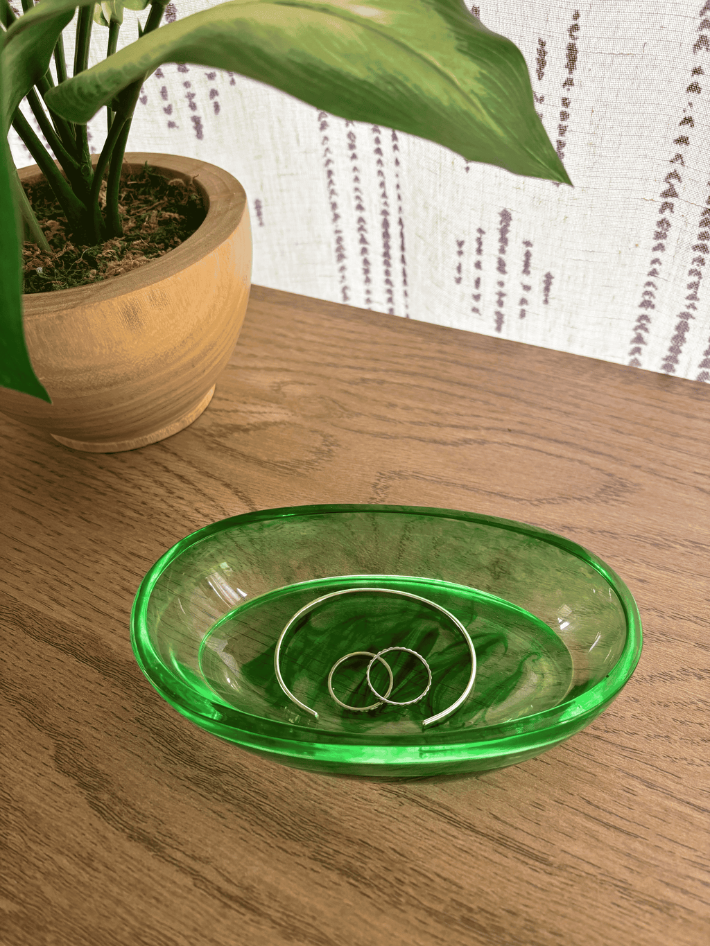 Oval resin tray with green swirls holding rings and bracelets