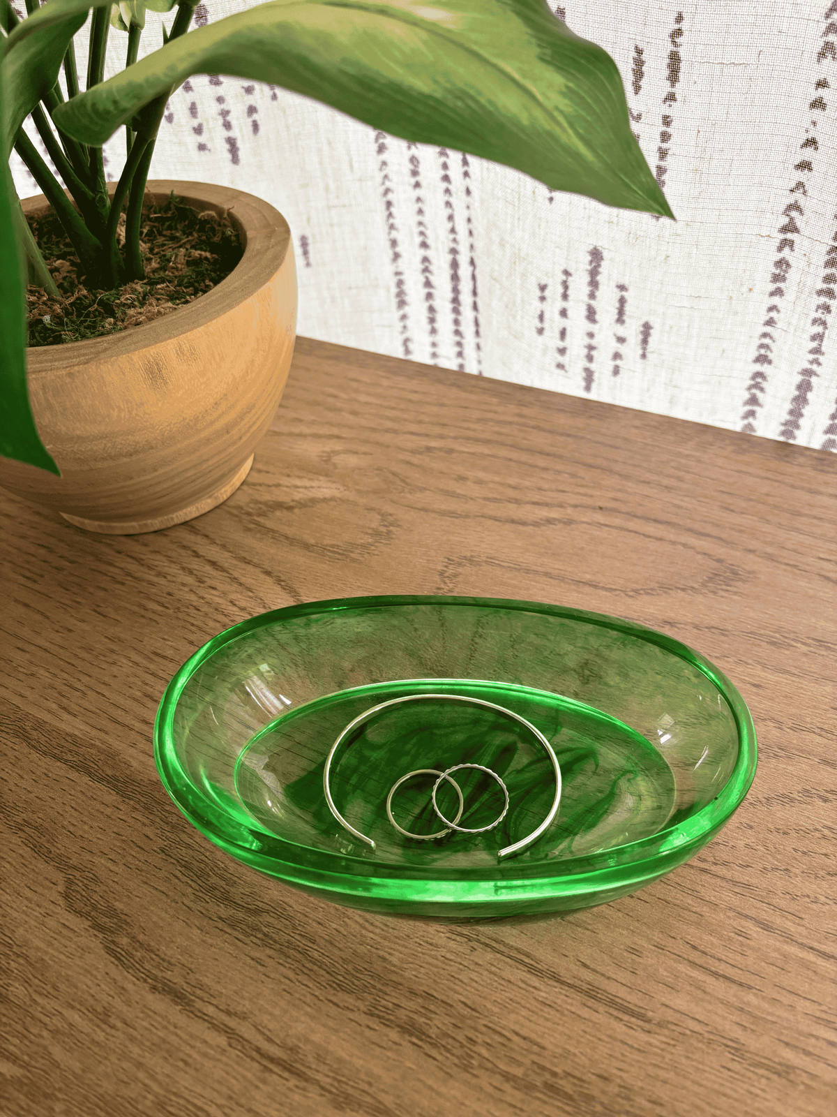 Oval resin tray with green swirls holding rings and bracelets