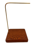 A brass and wood jewelry display stand featuring a textured reddish-brown wooden base and a curved brass rod, shown against a plain white background.