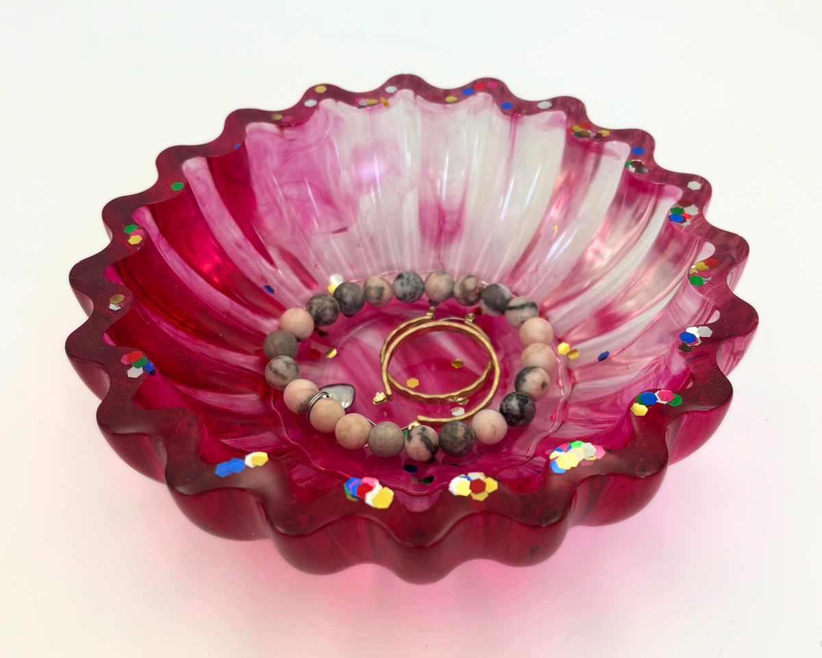 magenta resin bowl with confetti glitter and scalloped edges holding jewelry