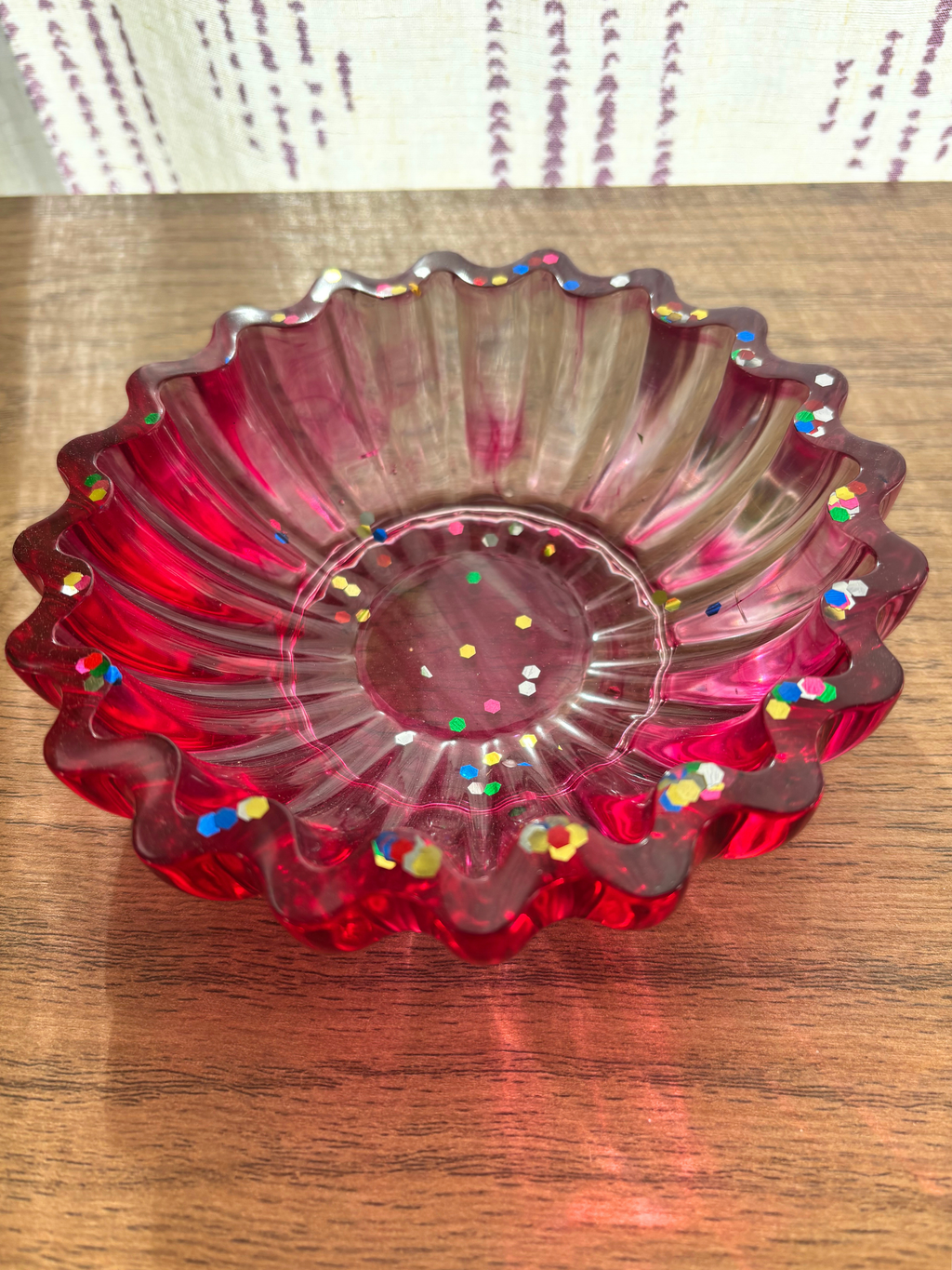 magenta resin bowl with confetti glitter and scalloped edges on table