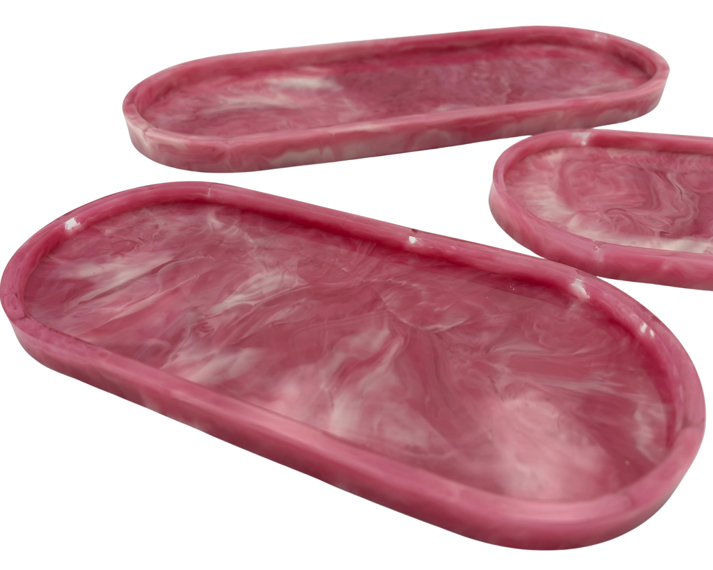 Three pink marbled resin trays with a swirled white pattern, shown on a solid white background.