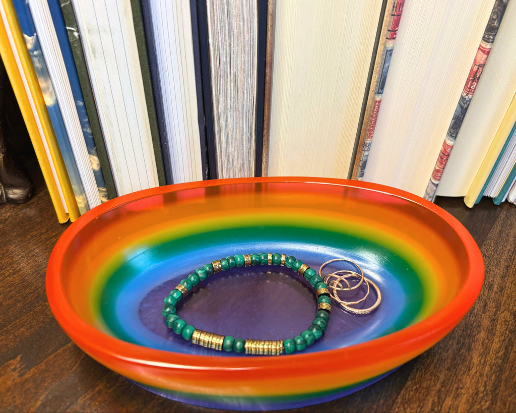 multicolored Oval Dish holding jewelry on a wooden table with a book background