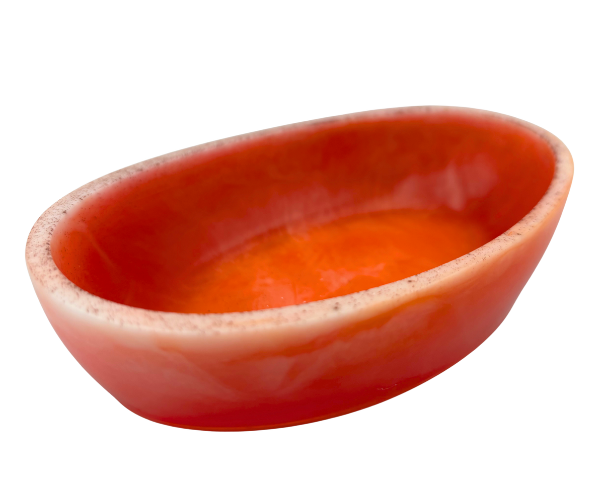 A small, shallow oval dish with orange swirls and a light rim, isolated on a white background.