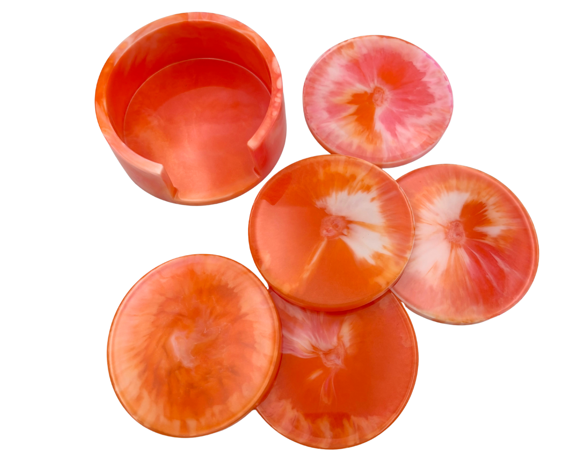 Set of resin coasters with holder; pink, orange, and white swirl pattern on a white background