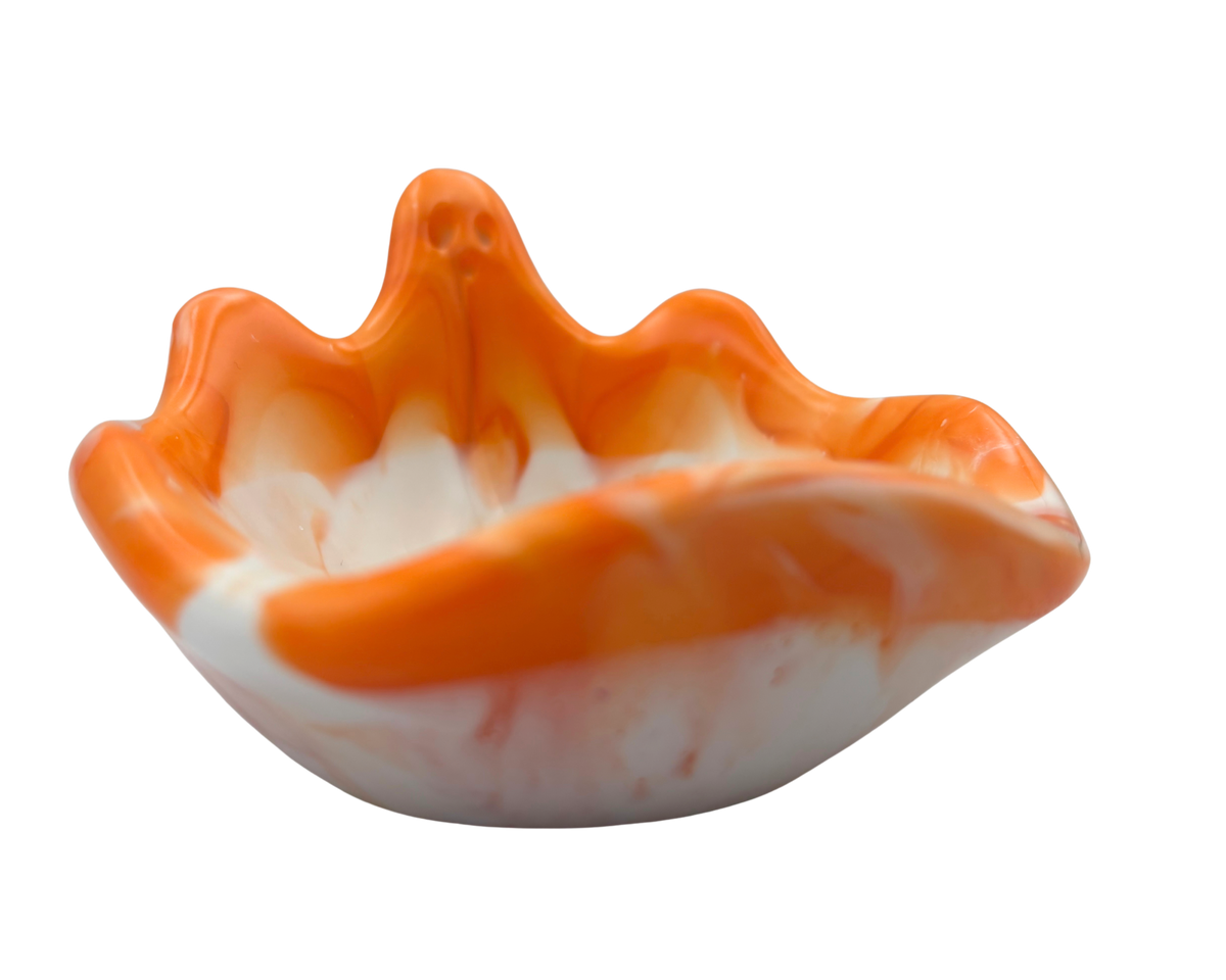 An orange and white marbled resin bowl with a ghost silhouette, photographed against a solid white background.