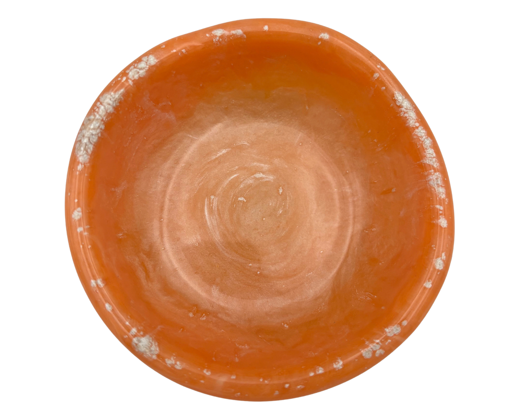 An orange resin ring dish, photographed from a top-down angle on a solid white background.