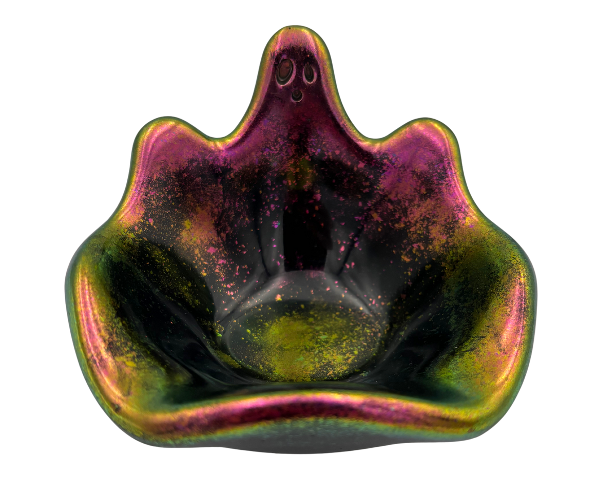 A small decorative bowl with a ghost-shaped silhouette, featuring an iridescent finish that shifts between green, gold, pink, and purple, with fine glitter inside.