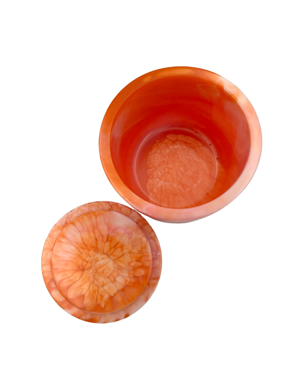 A cylindrical container with a lid, featuring a marbled design of vibrant orange, pink, and white layers, isolated on a white background.