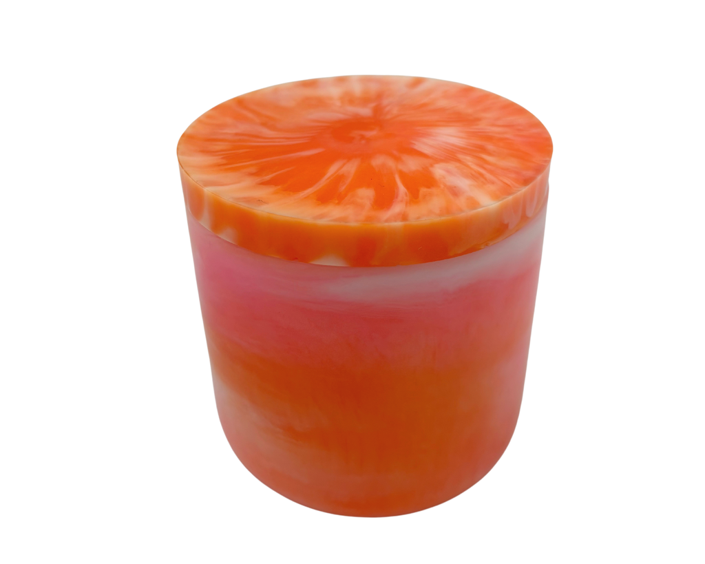 A cylindrical container with a lid, featuring a marbled design of vibrant orange, pink, and white layers, isolated on a white background.