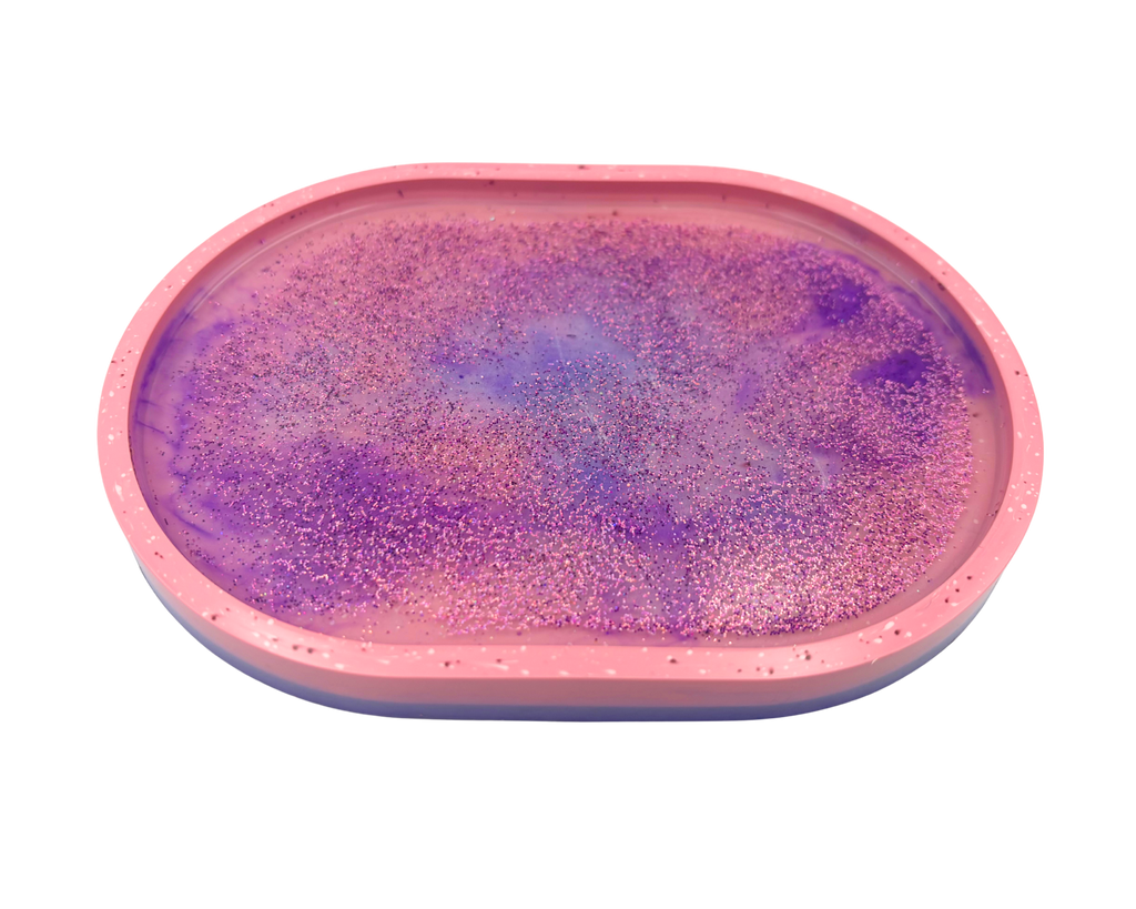 An oval-shaped pink tray or mold containing a purple glittery resin surface, shown against a plain white background.