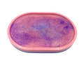 An oval-shaped pink tray or mold containing a purple glittery resin surface, shown against a plain white background.