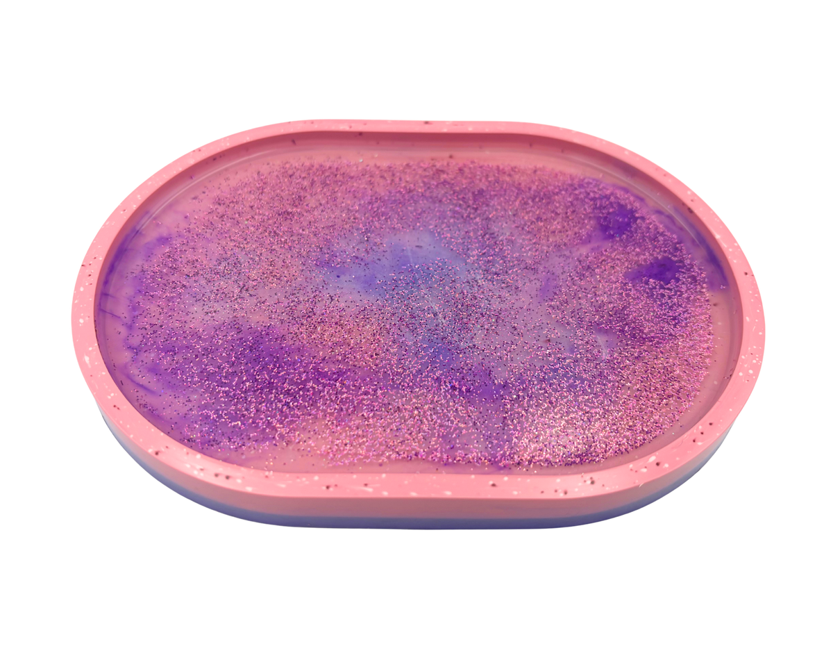 An oval-shaped pink tray or mold containing a purple glittery resin surface, shown against a plain white background.