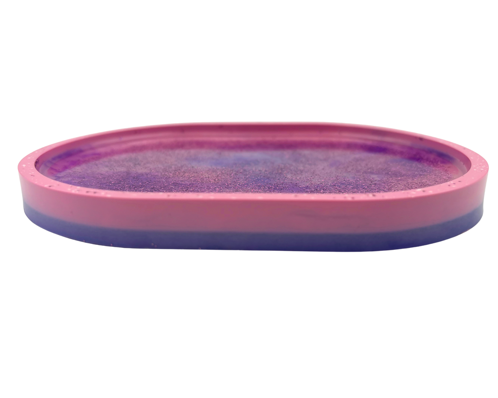An oval-shaped pink tray or mold containing a purple glittery resin surface, shown against a plain white background.