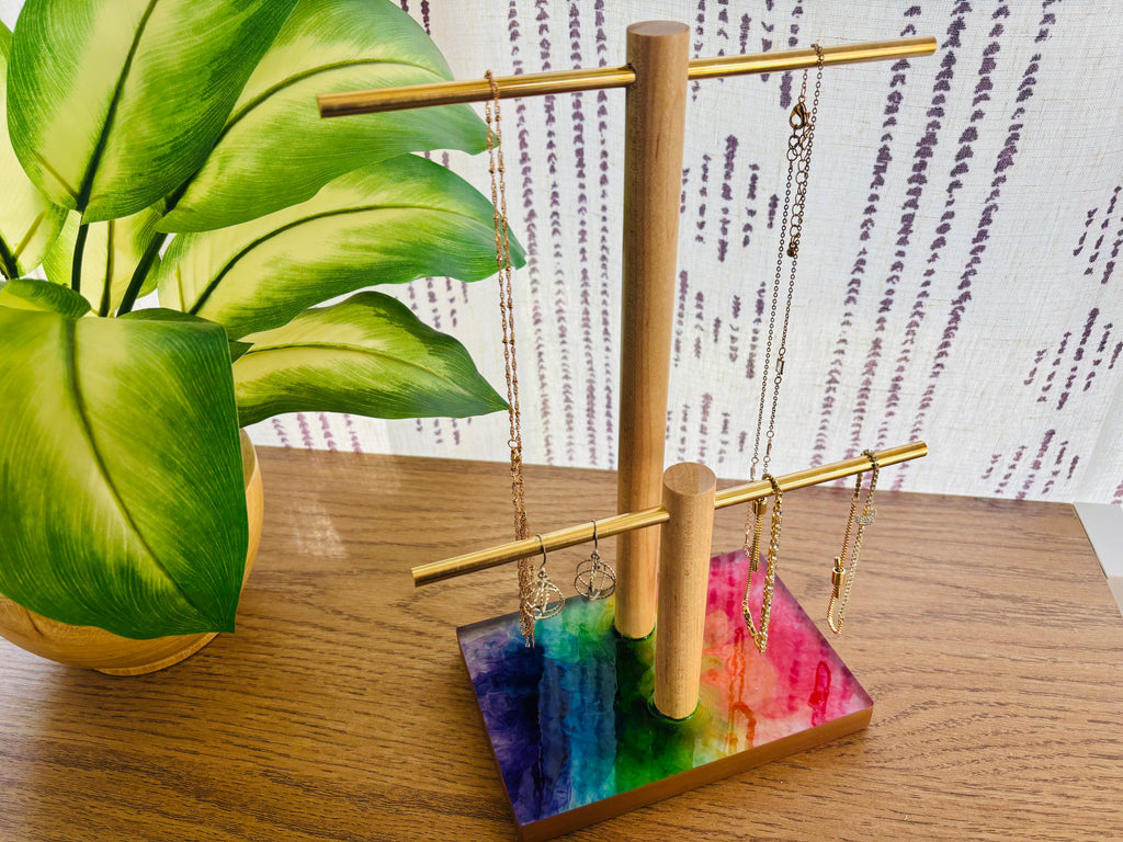 Jewelry stand with colorful base and hanging necklaces on table