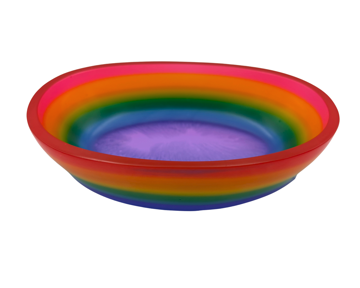 A shallow oval resin bowl with a vibrant rainbow gradient design, featuring concentric bands of red, orange, yellow, green, blue, and purple on a plain white background.