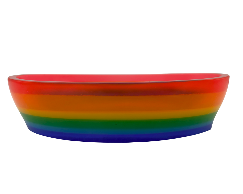 A shallow oval resin bowl with a vibrant rainbow gradient design, featuring concentric bands of red, orange, yellow, green, blue, and purple on a plain white background.