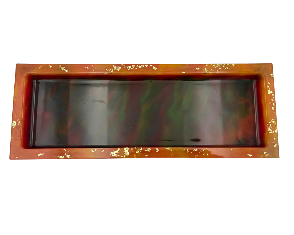 A rectangular resin tray with a glossy marbled pattern of deep colors and orange rim, accented with small gold flakes, shown on a plain white background.
