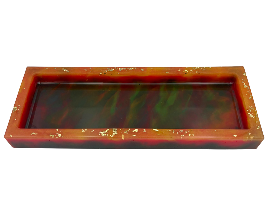 A rectangular resin tray with a glossy marbled pattern of deep colors and orange rim, accented with small gold flakes, shown on a plain white background.