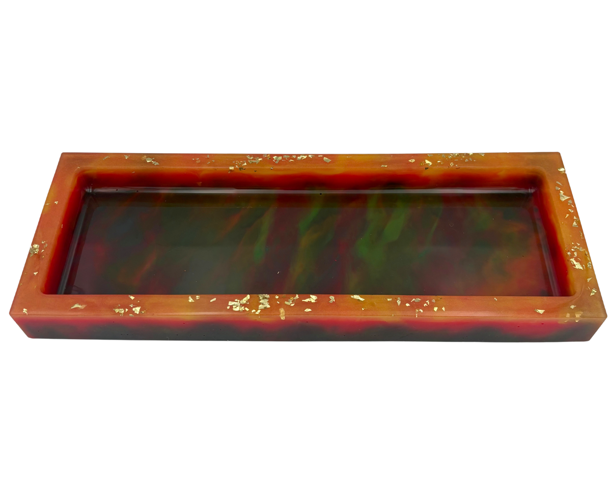 A rectangular resin tray with a glossy marbled pattern of deep colors and orange rim, accented with small gold flakes, shown on a plain white background.