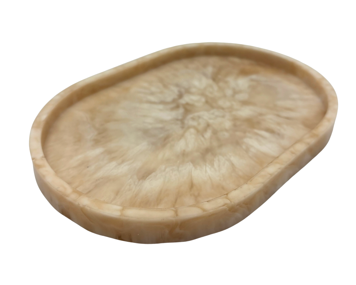 small oval Resin dish with beige and white marbled pattern on a white background
