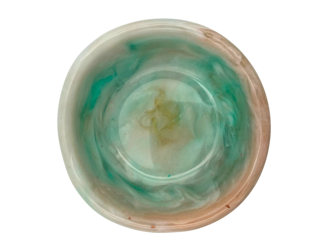 a small ring dish made of resin with teal and beige swirls on a white background