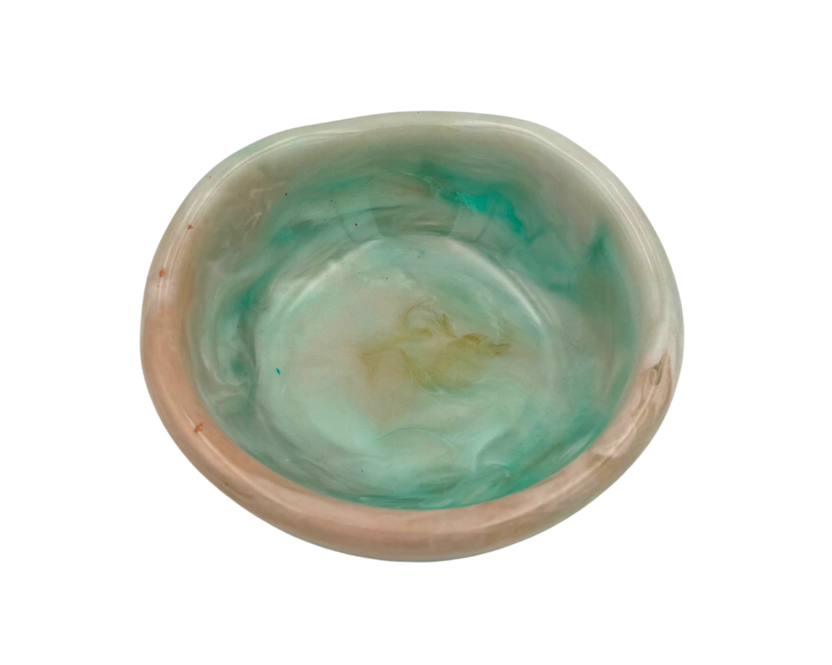a small ring dish made of resin with teal and beige swirls on a white background