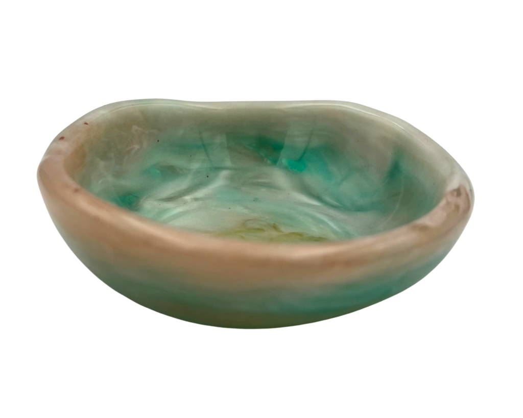 a small ring dish made of resin with teal and beige swirls on a white background