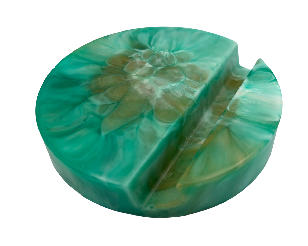 a round phone stand made of resin with teal and bronze patterns, on a white background
