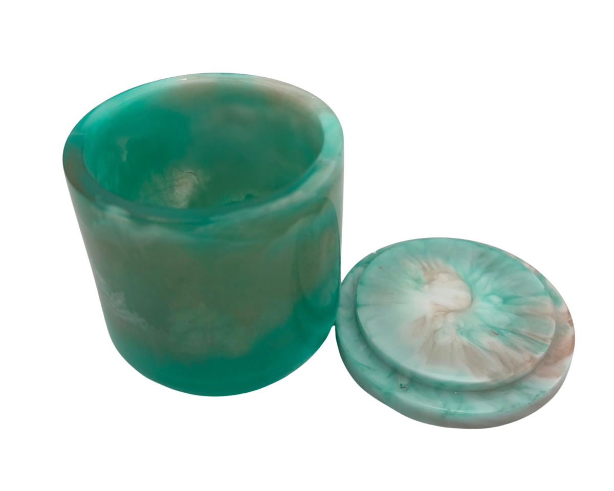 A cylindrical resin jar with a marbled green and white design, featuring a solid teal-green base and a swirled white and light teal lid.