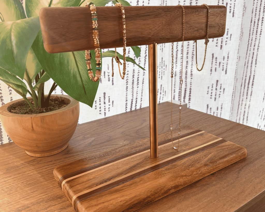 Wooden jewelry stand with a gold rod holding jewelry on table