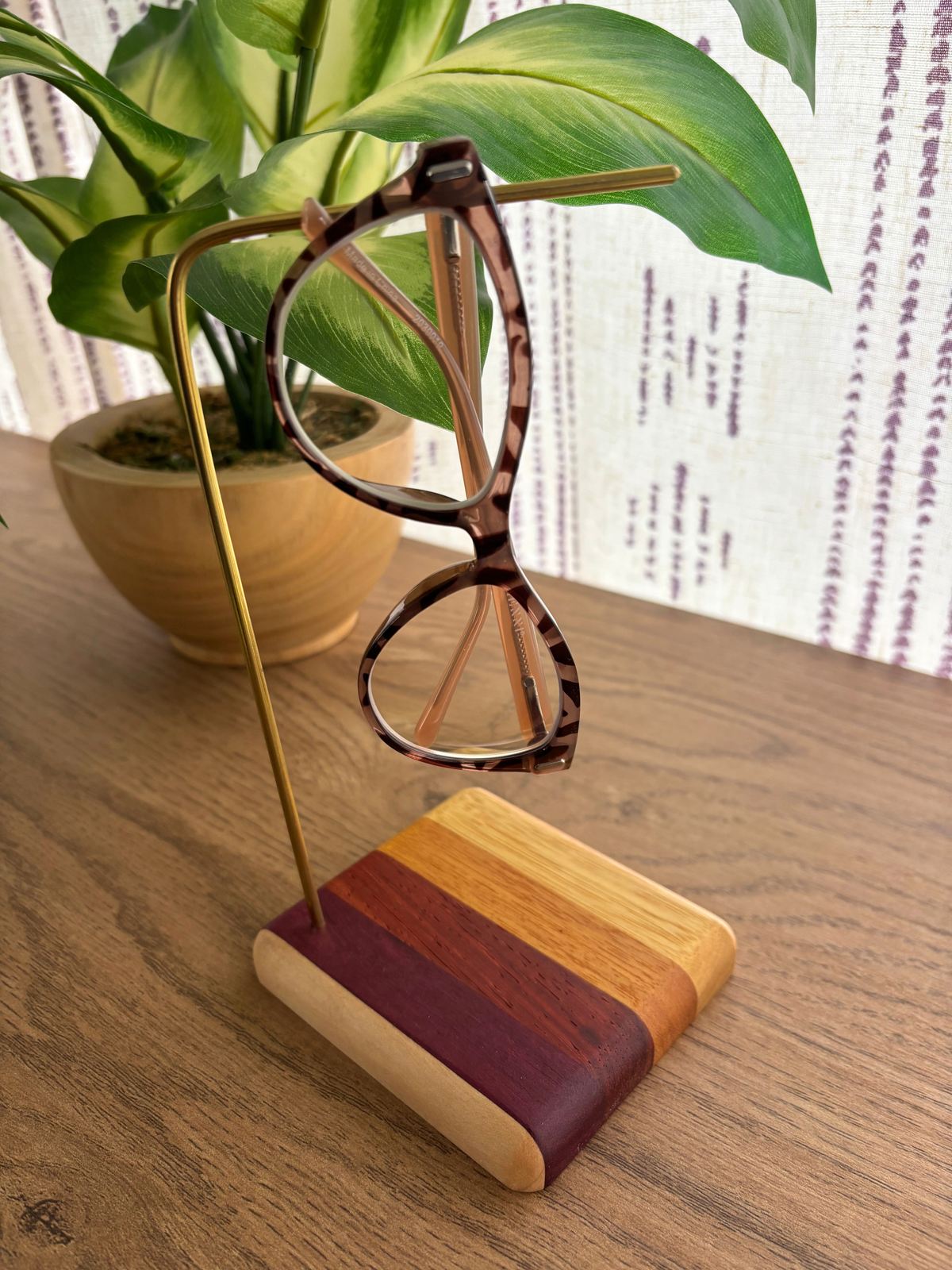 Glasses holder with wooden base and brass dowel holding pair of glasses on table