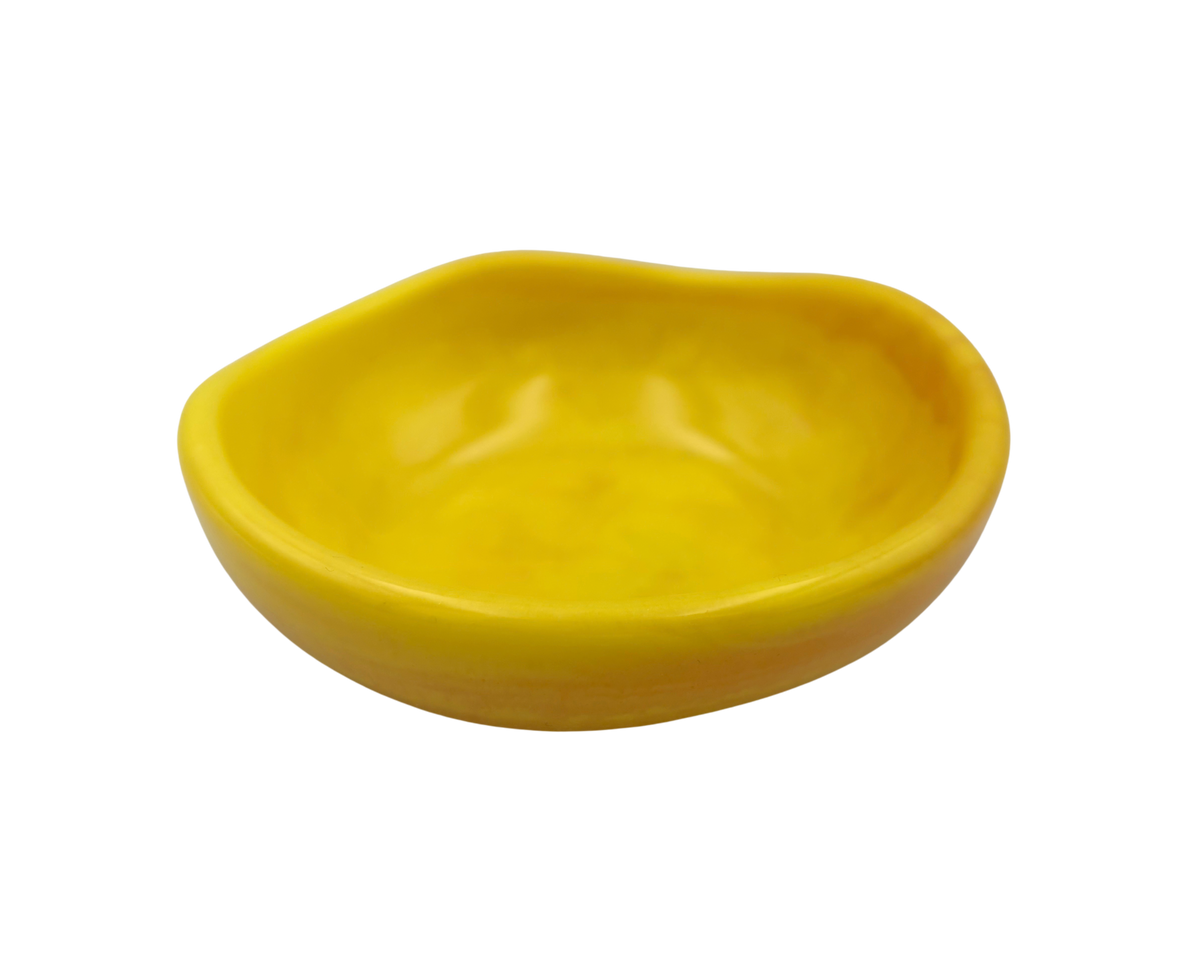 A small, organic-shaped yellow resin dish or shallow bowl, isolated on a solid white background.