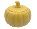 A yellow pumpkin-shaped resin lidded container with a ribbed texture and a short stem, shown on a plain white background.