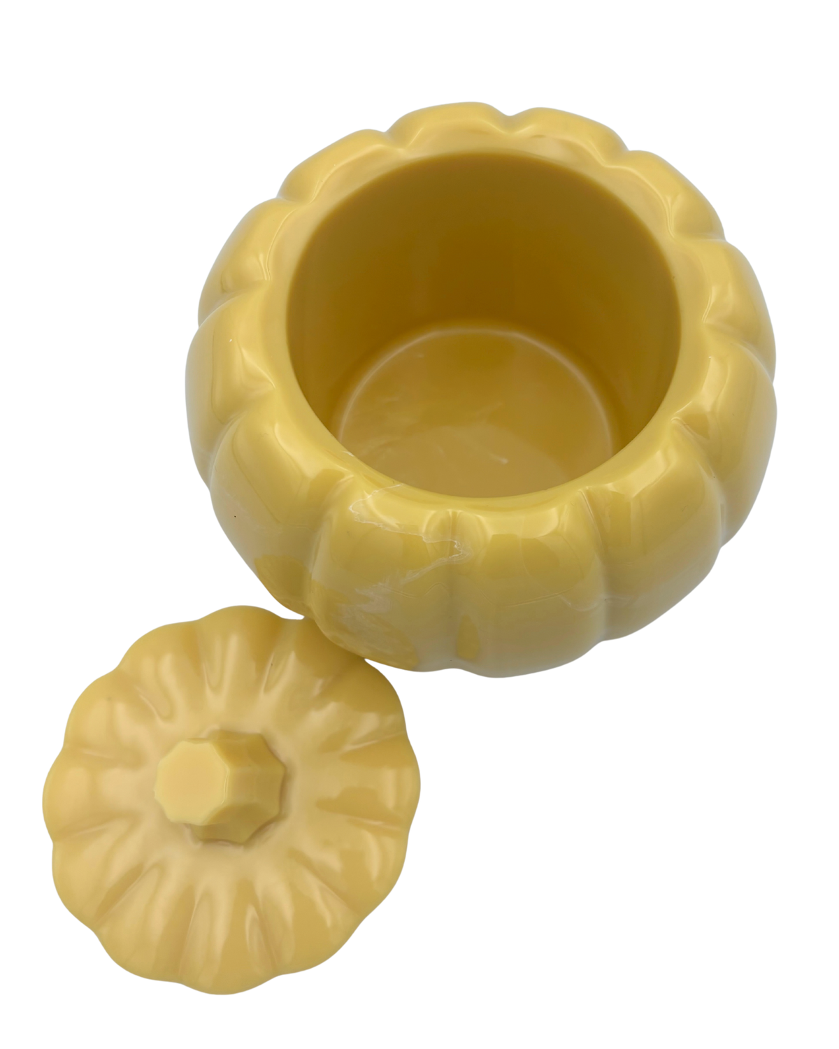 A small yellow pumpkin-shaped container with its matching lid placed beside it on a plain white background.